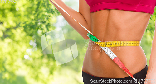 Image of close up of woman measuring her waist with tape