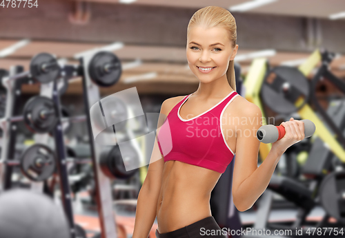 Image of happy woman training with light dumbbells in gym