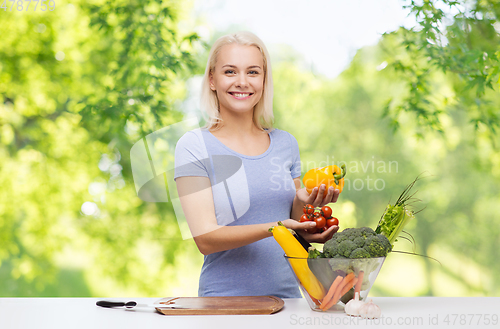 Image of smiling young woman cooking vegetables