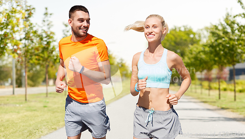 Image of happy couple with fitness trackers running outdoor