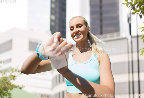 Image of happy woman with fitness tracker and earphones