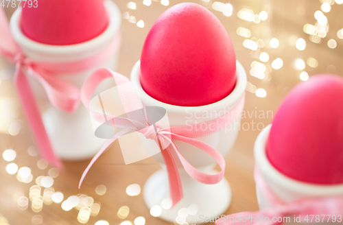 Image of pink colored easter eggs in holders on table