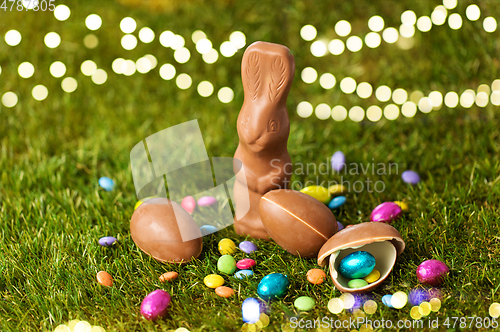 Image of chocolate bunny, eggs and candy drops on grass