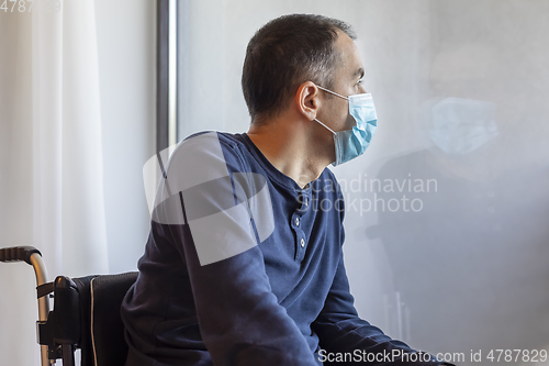 Image of Young man with medical mask looking out the window