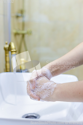 Image of Woman washing and disinfecting hands with soap and hot water