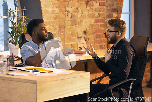 Image of Colleagues working together in modern office using devices and gadgets during creative meeting