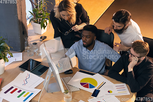 Image of Colleagues working together in modern office using devices and gadgets during creative meeting