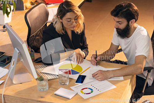 Image of Colleagues working together in modern office using devices and gadgets during creative meeting