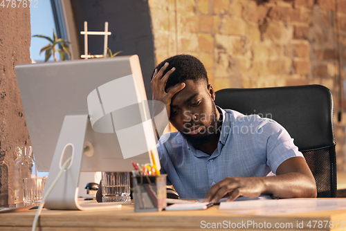 Image of African businessman, manager working in modern office using devices and gadgets