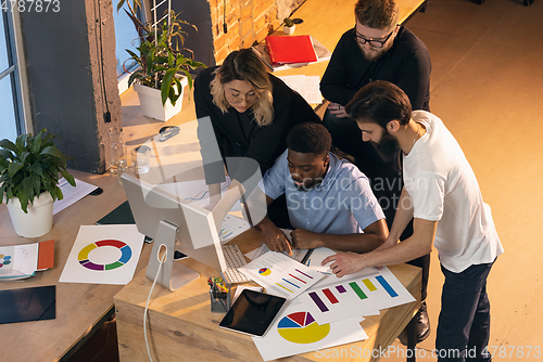 Image of Colleagues working together in modern office using devices and gadgets during creative meeting