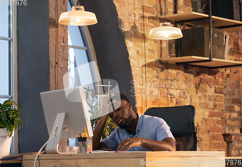 Image of African businessman, manager working in modern office using devices and gadgets