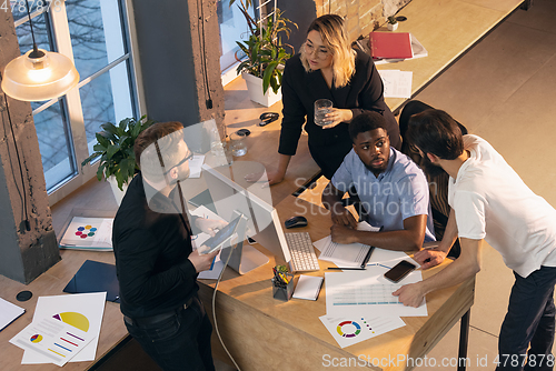 Image of Colleagues working together in modern office using devices and gadgets during creative meeting