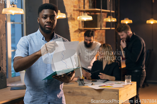 Image of Colleagues working together in modern office using devices and gadgets during creative meeting