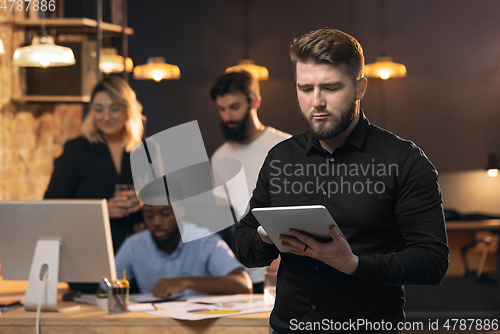 Image of Colleagues working together in modern office using devices and gadgets during creative meeting