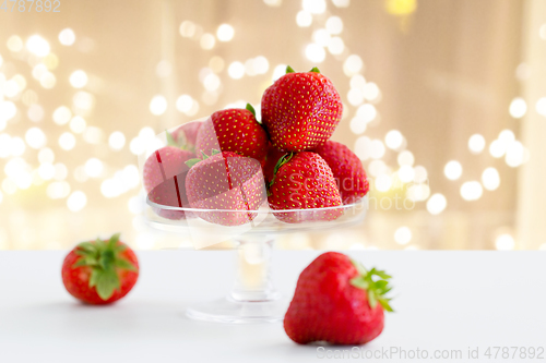 Image of strawberries on glass stand over white background