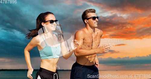 Image of couple with earphones running along on beach