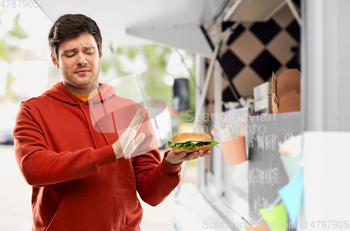 Image of young man refusing from hamburger at food truck