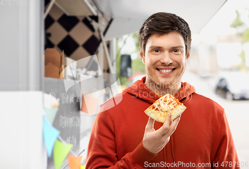 Image of happy young man eating pizza at food truck