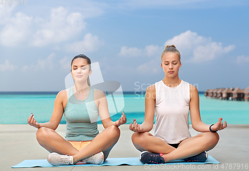 Image of women doing yoga and meditating in lotus pose