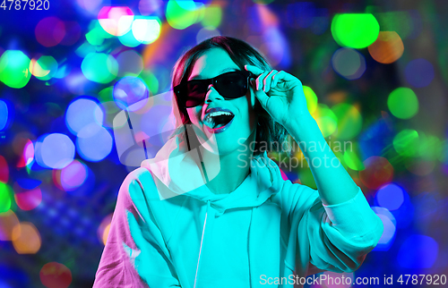 Image of woman in hoodie with sunglasses over night lights