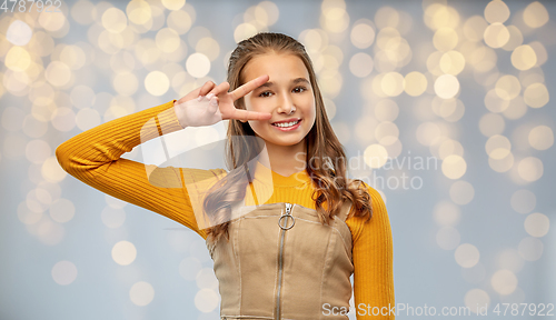 Image of smiling young teenage girl showing peace hand sign