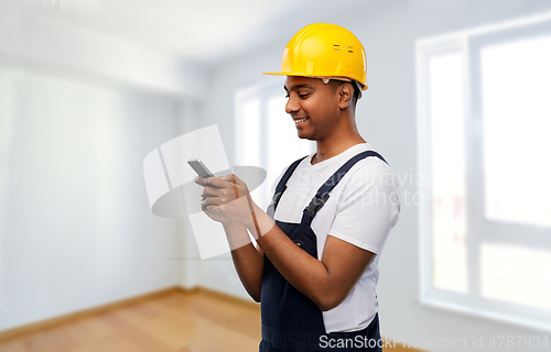 Image of happy indian or builder in helmet using smartphone