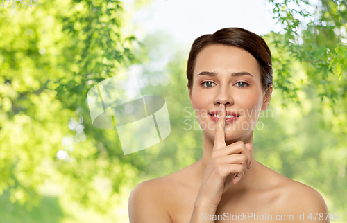 Image of beautiful young woman holding finger on lips