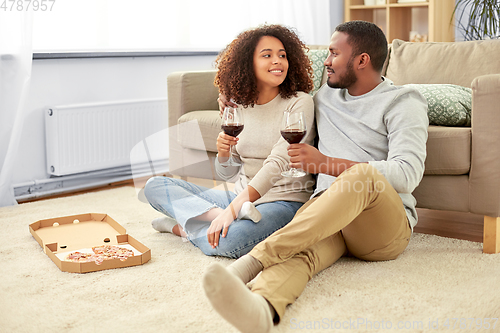 Image of happy couple with wine and takeaway pizza at home