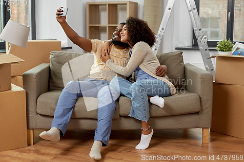 Image of happy couple moving to new home and taking selfie