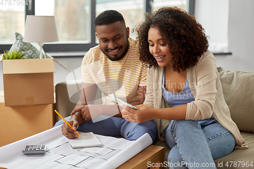 Image of couple with blueprint counting money at home