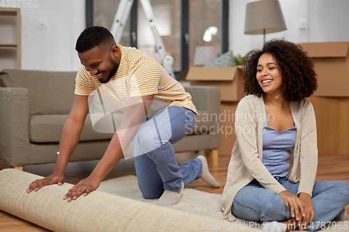 Image of happy couple with carpet moving to new home