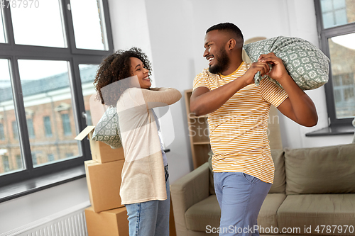Image of happy couple having pillow fight at new home