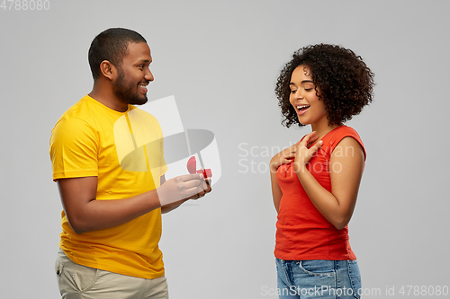 Image of african american man giving woman engagement ring