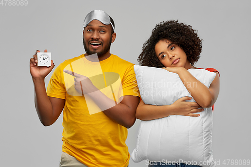 Image of couple with alarm clock, sleeping mask and pillow