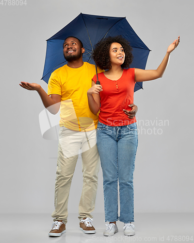 Image of smiling african american couple with umbrella