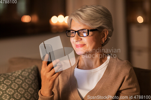 Image of happy senior woman with smartphone at home