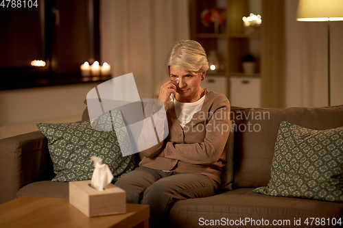 Image of crying senior woman wiping tears with paper tissue