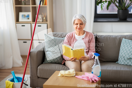 Image of senior woman reading book after home cleaning