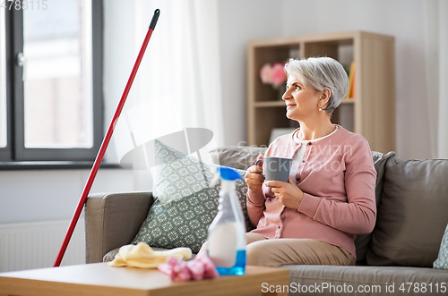 Image of senior woman drinking coffee after home cleaning