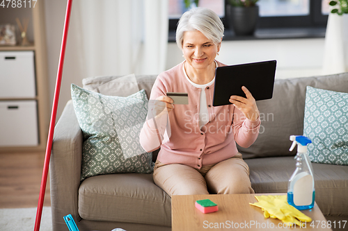 Image of old woman with tablet pc and credit card at home