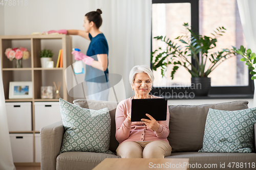 Image of old woman with tablet pc and housekeeper at home