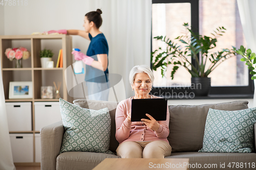 Image of old woman with tablet pc and housekeeper at home