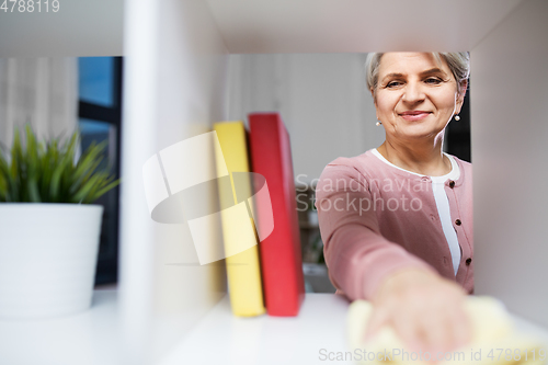 Image of happy senior woman with cloth dusting rack at home