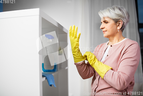 Image of senior woman putting protective rubber gloves on