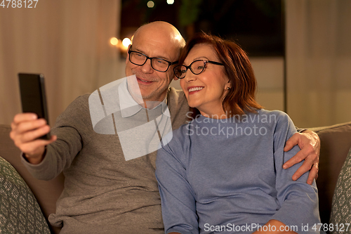 Image of old couple taking selfie with smartphone at home