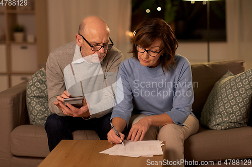 Image of senior couple with papers and calculator at home