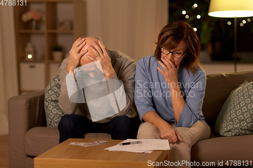 Image of unhappy senior couple with bills and money at home