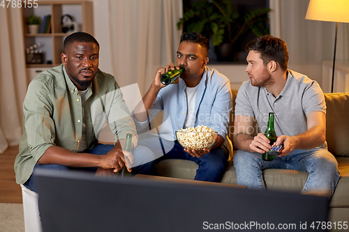 Image of male friends with beer watching tv at home