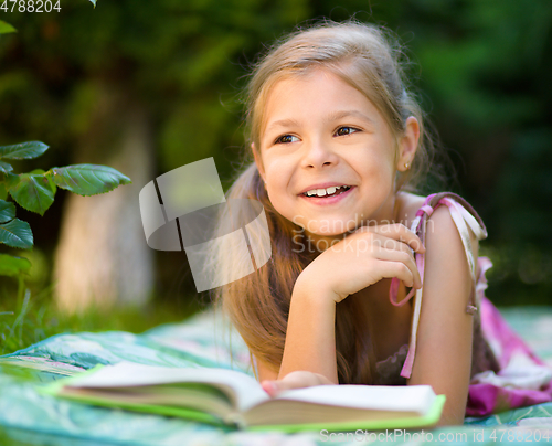 Image of Little girl is reading a book outdoors