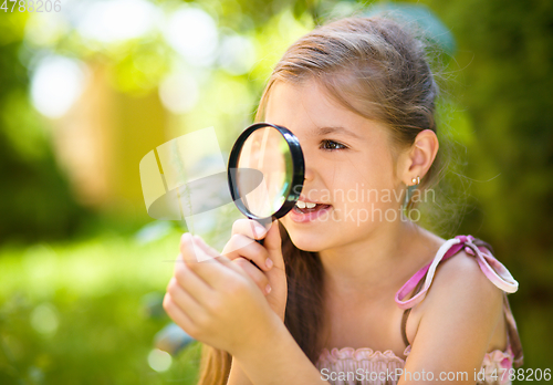 Image of Young girl is looking at flower through magnifier